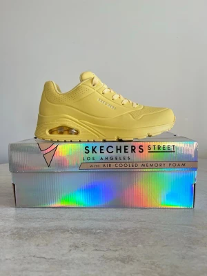 Gula Skechers sneakers Air-Cooled - Snygga gula sneakers från Skechers Street Los Angeles med Air-Cooled Memory Foam. Skorna har en chunky sula med synlig luftkudde, perforerade detaljer och klassiska snörningar. Perfekt för dig som vill sticka ut med färg och komfort.