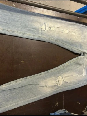 Ljusblå slitna dondup George  - Säljer ett par ljusblå dondup jeans med slitningar och hål på både lår och knän. Jeansen har en tvättad look och smal passform som ger en trendig och avslappnad stil. Oanvända ish tags finns