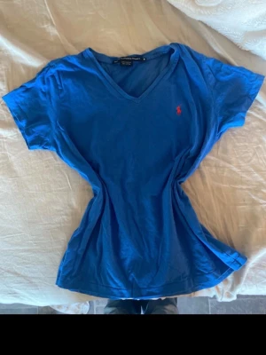 Blå vintage v-ringad t-shirt Ralph Lauren - Jätte snygg vintage t-shirt från ralph lauren❣️ den är i fint skick men lite nopprig, storlek M/S
