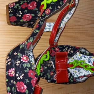 Otto et Moi slingback - Blommig svartbotten/röda rosor/grön kedja Klackhöjd:8,5 cm Tyg på ytter sida/lack Skinn som innerfoder och sula Str:38 Sparsamt använd sko