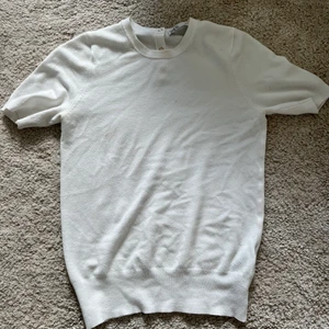 Vit finstickat lodern topp - En vit finstickad topp från zara med tre guld knappar bak på ryggen Använd ett fåtal gånger  Storlek S Köpare står för frakten