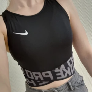 Croppad träningstopp Nike  - Croppad träningstopp i funktionsmaterial från Nike. Mycket sparsamt använd och i fint skick. Säljes pga garderobsrensning.