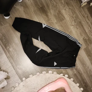 Adidas träningsbyxor  - Svarta adidas träningsbyxor med dragkedjor nertill på benen. Fickor på båda sidorna med dragkedjor.   Frakt betalas av köparen.