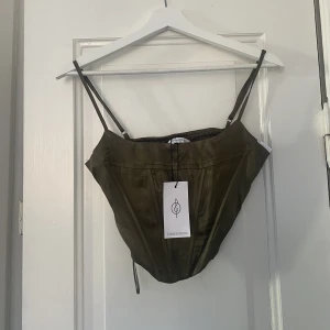 Korsett topp  - En helt oanvänd (prislappen kvar) korsett topp i satin material i en fin olivgrön färg.  I storlek S från strandivarius. 