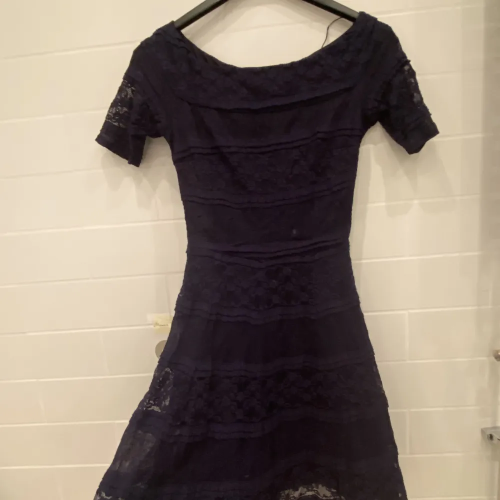 Fin marinblå klänning i spets med många volanger, med en tunn underkjol, är även lite off shoulder. Klänningar.
