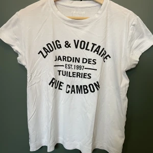Zadig & Voltaire T-Shirt - Vit T-Shirt från Zadig & Voltaire. Hittar inte storleken men det är en small! Bra skick förutom två minimala hål som man kan se på tredje bilden!