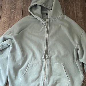 Brandy Melville Hoodie - En grå/grön hoodie från Brandy Melville. Den är i bra skick. Orginal priset är ungefär 400kr. Köparen står för frakten!