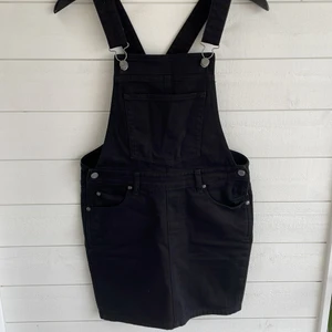 Hängselklänning - Snyggt att kombinera med en polotröja eller t-shirt under. Mycket fint skick. Har fickor både fram och bak, hängslena går att reglera. Det är jeansmaterial, men mycket strechig så den är bekväm att bära. Köparen står för fraktavgiften. 