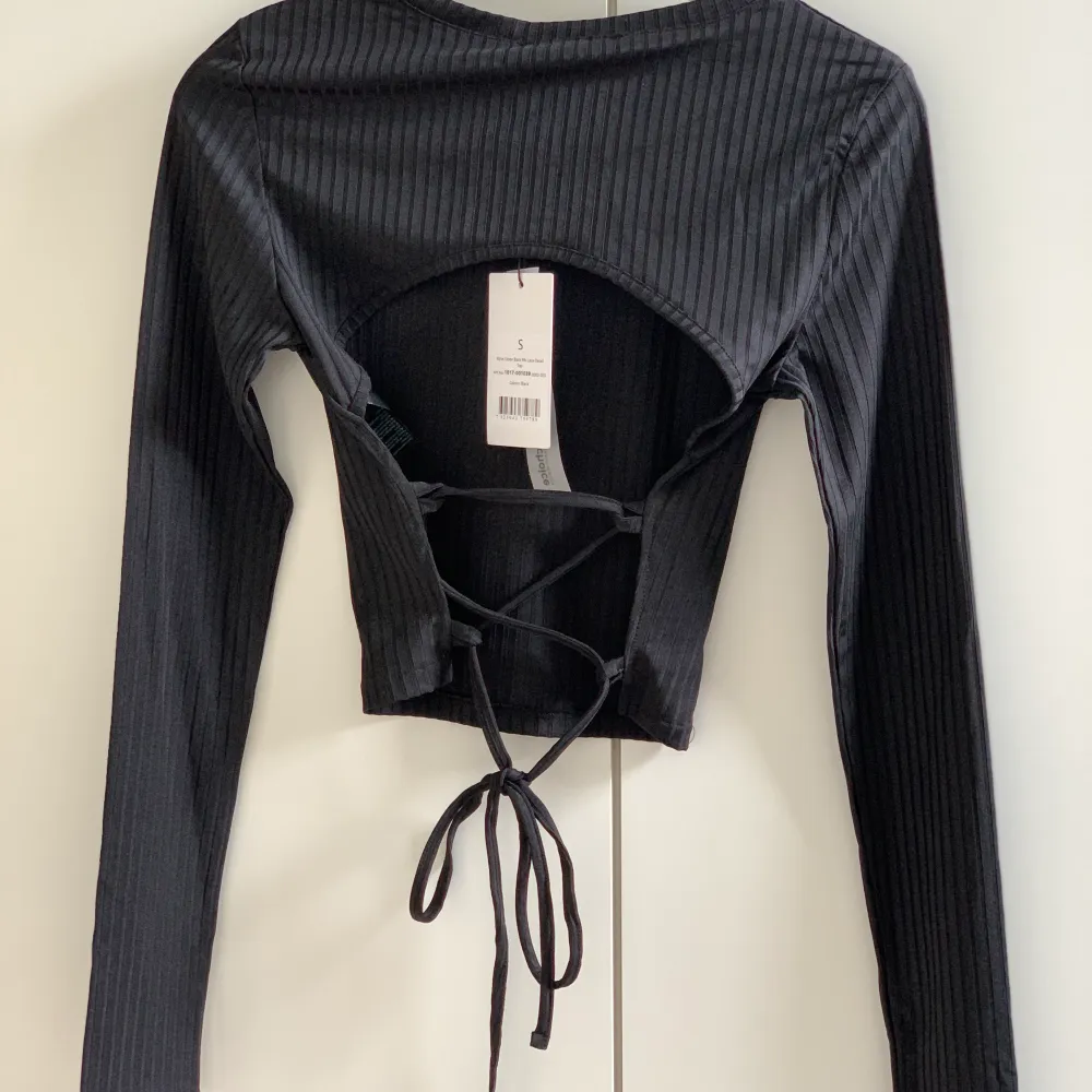 Svart tröja med öppen rygg från NA-KD i storlek S. Tröjan är helt oanvänd och har lappen kvar. Säljer för 150kr+frakt😊. Toppar.