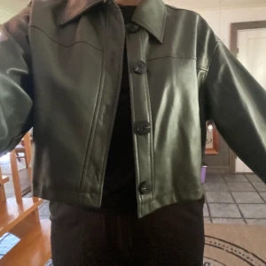Croppad jacka - Skitsnygg fejk-läder jacka i en mörk/militärgrön färg. Tycker verkligen den är jättefin men den kommer tyvärr inte till användning.  Använd endast 3 ggr så den är som ny!   Nyköp runt 500kr. Köpare står för frakt Skriv vid intresse eller fler bilder🤎