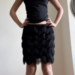 Kjol - Svart kjol med hängande fransar som nästan räcker ner till knäna
