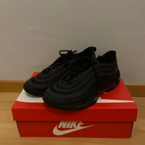 Nike Air Max 97 - Detta är mina hel svarta Nike Air Max 97 som jag köpte för en vecka sen från Nike. Jag vill sälja dessa skor för att jag inte använder de. Jag har bara använt de 3 gånger. Jag köpte de för 2049kr och säljer de för 999kr. Köparen står för frakten! PayPal