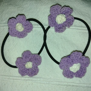 Två hårsnoddar med virkade blommor - Två svarta hårsnoddar med lila/vita virkade blommor. Tror att de är köpta på H&M och att de är helt oanvända. 