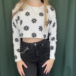 Blommig cropped kofta - Jättesöt blommig croppad kofta. Färgen är vit/ljusblå med svarta blommor och den är perfekt längd då den inte täcker midjan!