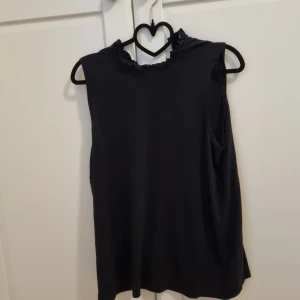 Superfin svart topp - Svart topp med krusad halsringning, jättefin och mjukt material. Storlek S.