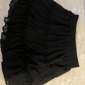 Svart volang kjol - Svart volang kjol andvänd Max 5 gånger och fin kvalite med små prickar på