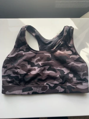Casall träningsbh- oanvänd! - Säljer en helt oanvänd sport-bh från Casall. Supersnygg med camouflage mönster. Medium-hård så den fungerar bra till de flesta sporter såsom löpning, spinning, högintensiv träning. Nypris 350 kr.