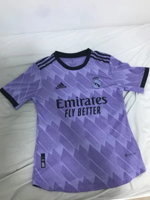 Real Madrid borta ställ 2022/23 - Real Madrid bortaställ 22/23 player version. Vini Jr på ryggen storlek S, använd få gånger. Det ända som är ett minus är den lilla fläcken vid klubbmärket, men som syns knappt inte. Säljer denna tröja för 300kr.