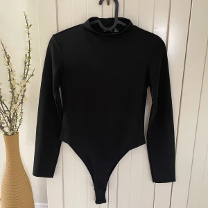  Body  - Sval svart body som är lite see-through, har knäppbara knappar nertill 