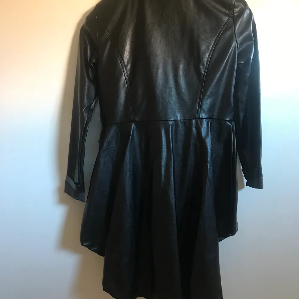 Asymmetrisk jacka i faux leather. Längd fram vid blixtlås 60cm, baksidan 97cm.. Jackor.