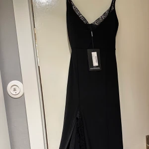 Långklänning svart  - Helt oanvänd svart långklänning med slit och fina spetsdetaljer, tyget är fint!  Köparen står för frakt.  Klänningen är i storlek S/XS