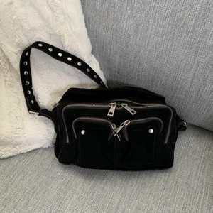 Núnoo väska  - Säljer mina núnoo väska som knappt blivit använd. Snygg väska i svart med nitar. Köpt på zalando för 1495kr. Skicket är precis som nytt. Säljer för 600kr. Bandet till väskan medföljer och har aldrig blivit utplockat ur förpackningen. Skickas spårbart! 