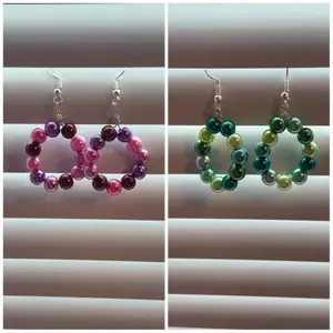 Handgjorda örhängen i lila/rosa pärlor eller grön/blåa pärlor. Du som kund väljer mellan färgerna, att kombinera går även toppen bra 👍  Kunden står för frakt
