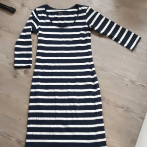 Vit/Blårandig Klänning - Marinblå klänning med vita ränder och 3/4 ärmar. Den är Strl 34/36 men den passar om man brukar ha lite större storlek. Aldrig använd.