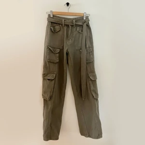 Emmiol gröna cargo byxor med tillägbart bälte - Gröna cargobyxor i använt skick. Köpta online med tillägbart bälte. Dragkedjan är lite trög!