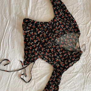 Söt blus - Söt liten blus fr hm. Knyts i sidan. Tar fram midjan fint. Har knapp så den ej blir för urringad. Motiv är typ rönnbär tror jag men ser ut som körsbär