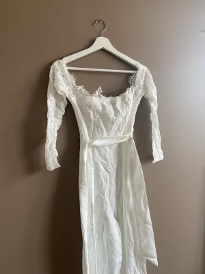 Jumpsuit - Vit jumpsuit med spets och band i midjan. Överdelen är offshoulder. Från Boohoo. Prislappen kvar