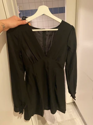 Svart festklänning  - Svart klänning i halv kort modell med liten slits