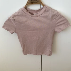 Croppad t-shirt - (Bilden är lite missvisande då det ser ut som t-shirten är randig vilket den inte är, den är helfärgad). Köpte på HM för cirka 1 år sedan och har vuxit ur den. Använd fåtal gånger.