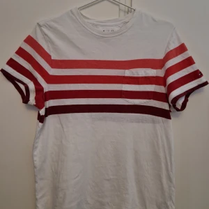 Tommy Hilfiger T-shirt - Köptes i USA för några år sedan. Den är rätt välanvänd, men enda tecknet på slitage är att texten i nacken börjat försvinna. Den är en Amerikansk xs, vilket betyder att den sitter mer som en S. Jag kan fortfarande ha den o jag väger 75 kg. Buda på!
