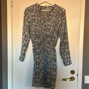 blommig klänning  - långärmad blommig klänning med knyte i midjan. sparsamt använd