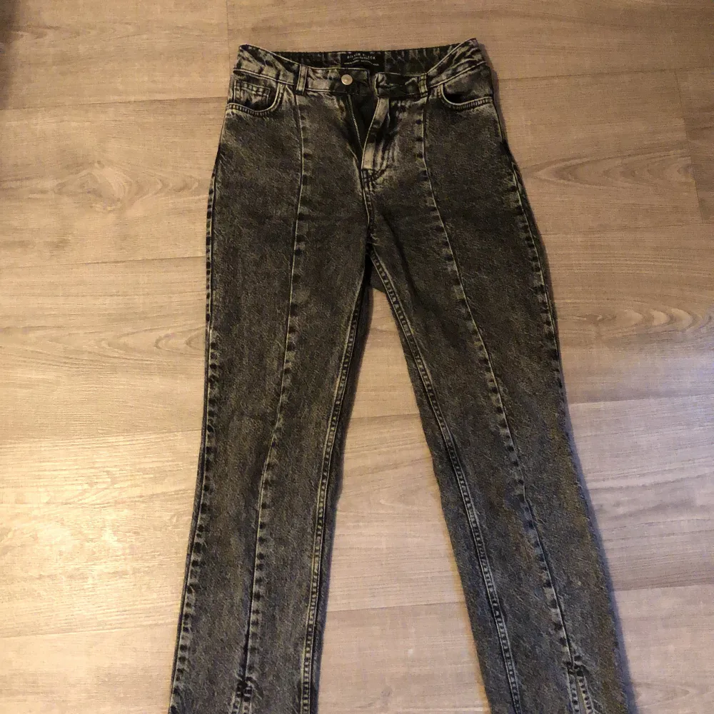 Snygga och sköna jeans i en mörkgrå färg. Sömm i mitten av benen och med slits längs ner. Skulle säga att jeansen är lågmidjade/midwaist . Jeans & Byxor.