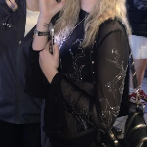 Genomskinlig festtopp - Säljer denna genomskinliga svarta tröjan med glitterdetaljer från weekday. 