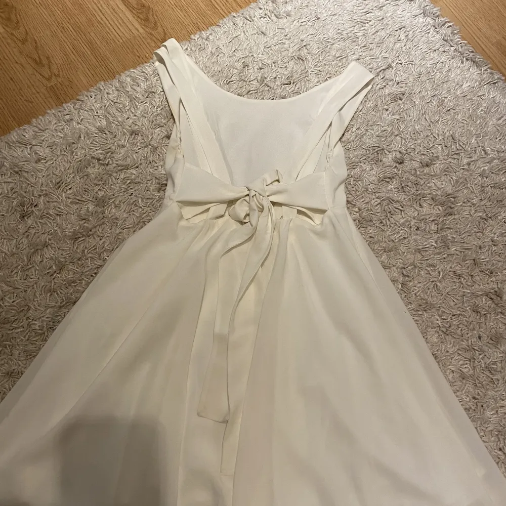En fin vit klänning som ha en roset i ryggen . Klänningar.