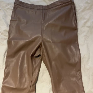 Skinbyxor  - Bruna skinbyxor från Nelly. Slits och dragkedja på vänster sida  