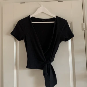 Ribbad knytblus storlek M - Svart ribbad knytblus från Gina!