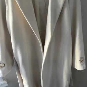 Vit kappa  - Lång kappa, med guld detalj vid ärmarna. Overaize