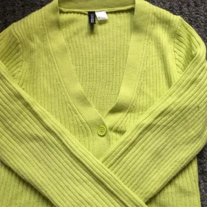 Grön kofta - En söt grön/gul kofta från hm! Den ser mer gul ut på bilden men den drar mer åt det gröna hållet! Kontakta vid intresse! Frakt tillkommer :)