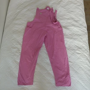 Rosa hängselbyxor - Ett par tuggummirosa hängselbyxor. Passar en L-XL.