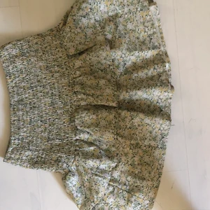 Grön blommig volangkjol  - Jag säljer en grön volangkjol med gula, vita och gröna blommor på! Den är från shein och är i jättefint skick, supersöt verkligen! Hör av er vid frågor eller fler bilder!