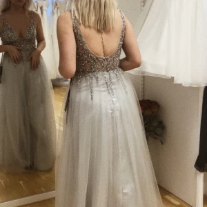 Balklänning  - Säljer min balklänning från för förra årets bal. Endast använd på bal tillfället. Den är grå/ silvrig med silvriga stenar och mesh på överdelen. Den är i size 10 vilket motsvarar  38/M. Nypris 4000