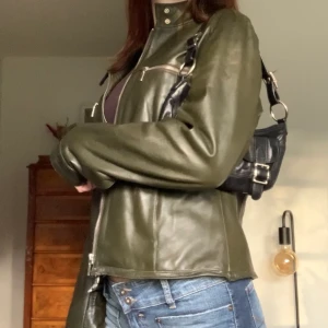 Grön skinnjacka - Skinnjacka i bikermodell med silverdetaljer, från Hennes alltså vintage H&M! Står stl 42 men passar mig som brukar ha XS/S (sliten på insidan längst ner, men syns inte utåt) 💕