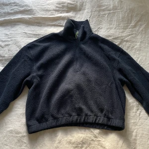 Fleece från Weekday - En mörkblå fleece, dragkedja med neongrön detalj. Lite croppad i modellen. Resor i slutet av ärmar och vid änden av tröjan.