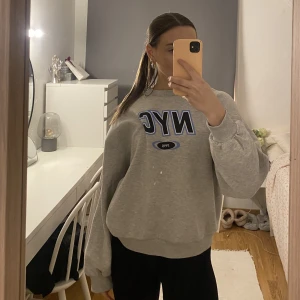 Grå Sweatshirt - Säljer denna ljusgråa sweatshirt från Gina Tricot med trycket NYC på. Ganska använd och där med lite nopprig, men tror det ska gå att ta bort!  Tröjan är i strlk S🤍 Köparen står för frakten!