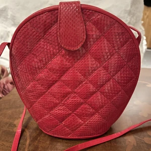 Röd axelväska - Lite rolig, röd axelbandsväska. Likt ormskinnsmönster 