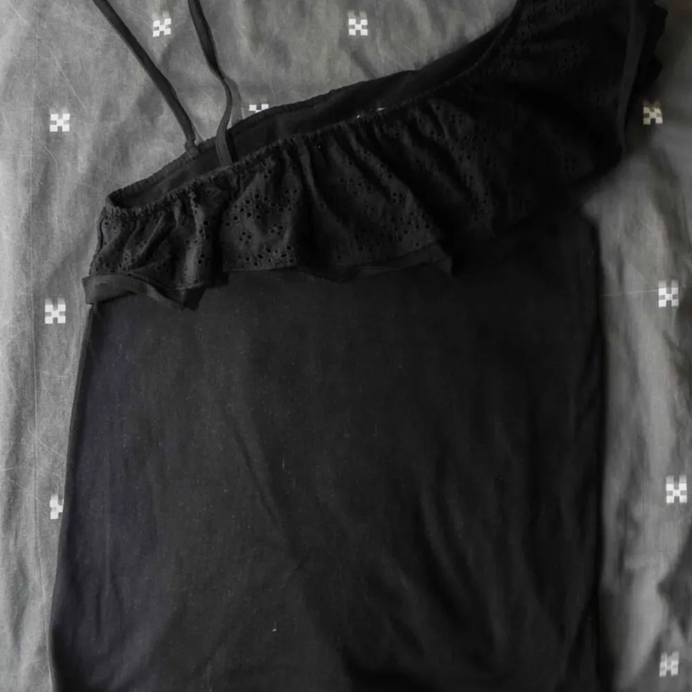En enkel svart blus med volang på ena ärmen.  Ny och endast använd en gång.  Tunn och luftig, perfekt för sommaren.. T-shirts.